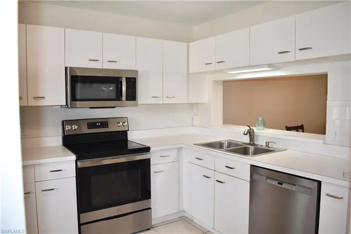 Kitchen with stainless steel appliances, white cabinetry, light tile patterned floors, and pass-through to Dining Room