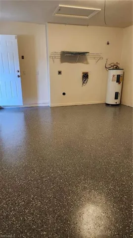 Laundry area with water heater, electric dryer hookup, and speckle patterned floor