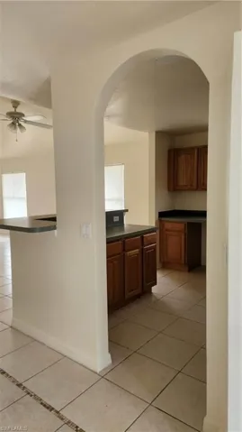 Hallway with light tile patterned flooring and arched walkways
