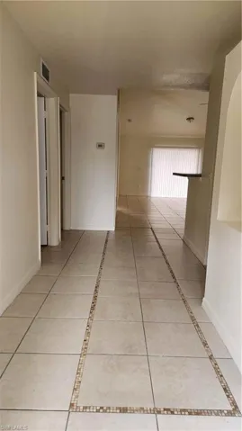 Hall with inlaid floor details and light tile patterned flooring