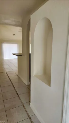 Corridor featuring light tile patterned floors and arched walkways