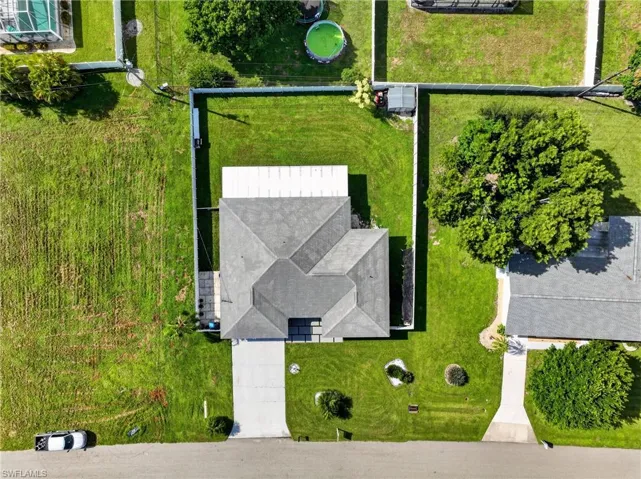Pitched roofline, concrete driveway, fenced yard, and a paved walkway