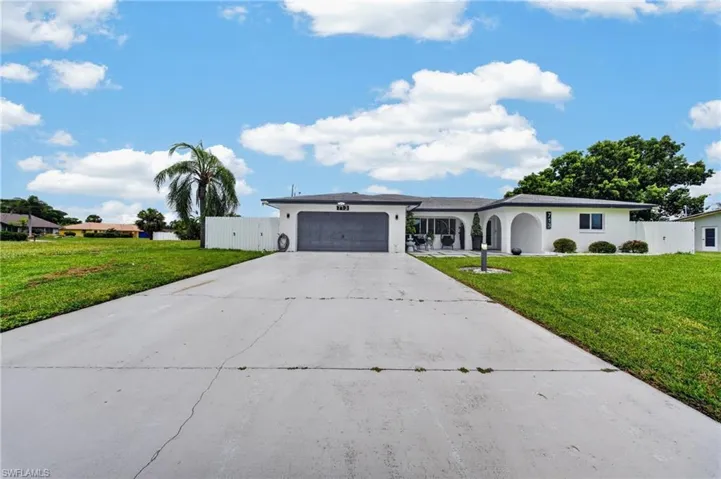 Single-story residence featuring a white exterior, attached garage, and arched entryways