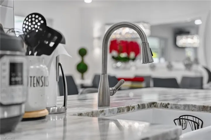 Gooseneck pull-down faucet with a single-handle design, integrated into a white sink basin, set within a polished stone countertop