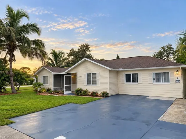 Single-story residence featuring light-colored siding, a dark roof, a screened entryway, and a paved driveway