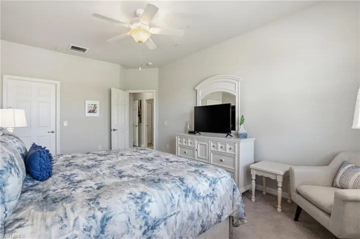 Relaxing bedroom for visitors with neutral colors, a sitting area, and classic plantation shutters.