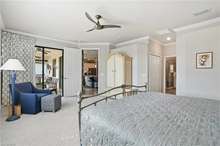 Inviting primary bedroom with crown molding, plantation shutters, lanai access, sitting area, and his-and-hers closets with custom built-ins.