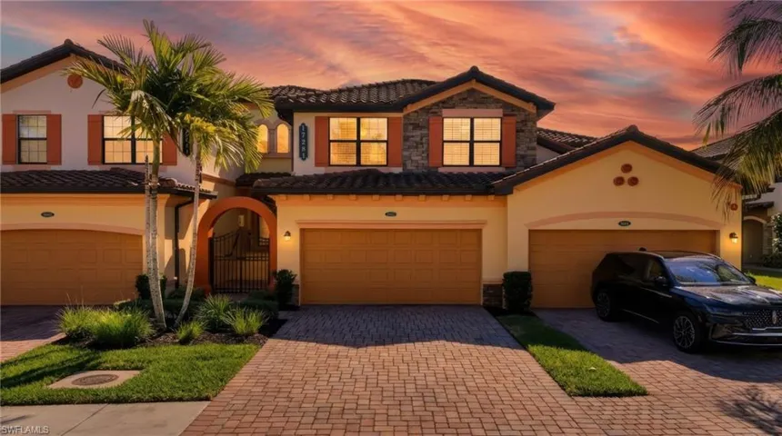 Coach home condo 2nd floor, featuring stone & stucco siding, entry gate, and decorative driveway
