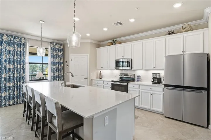 Bright open-concept kitchen showcasing white cabinetry, quartz counters, a designer backsplash, and a soothing neutral palette accented by designer drapery.