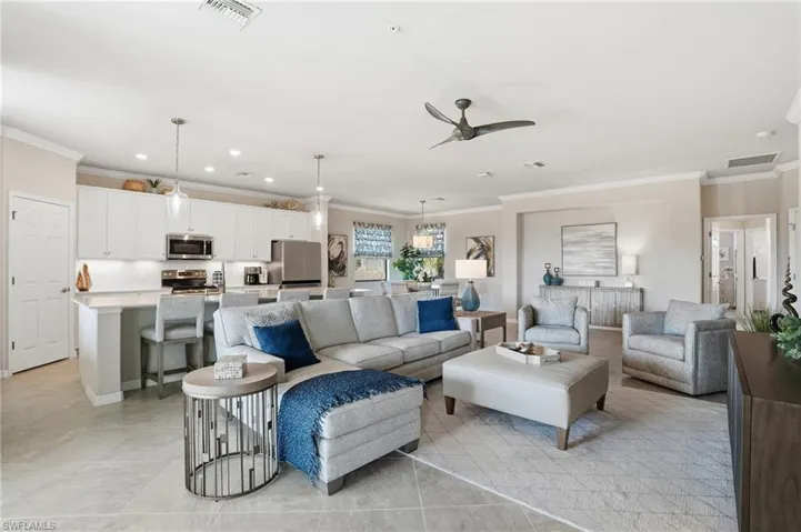 Stylish living room with crown molding, recessed lighting, a contemporary fan, and an open-concept modern kitchen.