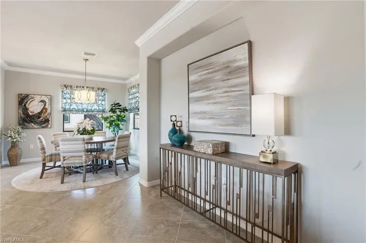 Charming dining area showcasing crown molding, a decorative table setting, and a classic chandelier.
