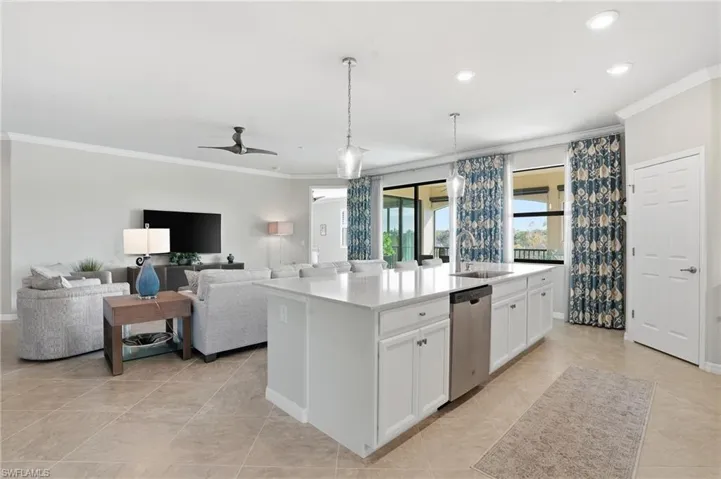 From the dining area, the open-concept layout reveals a bright kitchen with white cabinetry, quartz countertops, and a spacious island flowing into the living room.