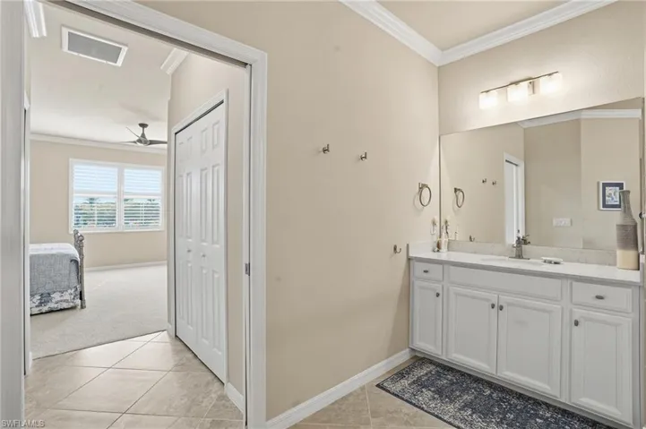 Full primary bathroom with crown molding, two vanities, generous shower, patterned tile floors, and ample space.
