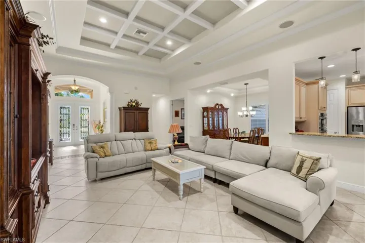 Living room featuring beamed ceiling, french doors, a high ceiling, light tile patterned flooring, and coffered ceiling