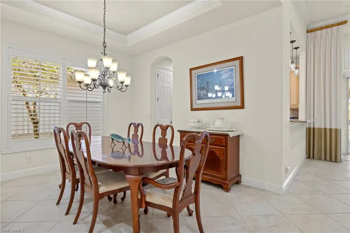 Tiled dining space featuring a chandelier, crown molding, and a tray ceiling