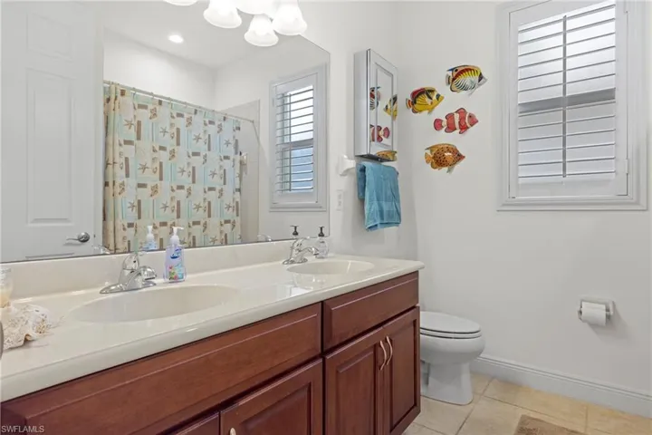 Bathroom featuring dual vanity, tile patterned floors, and toilet