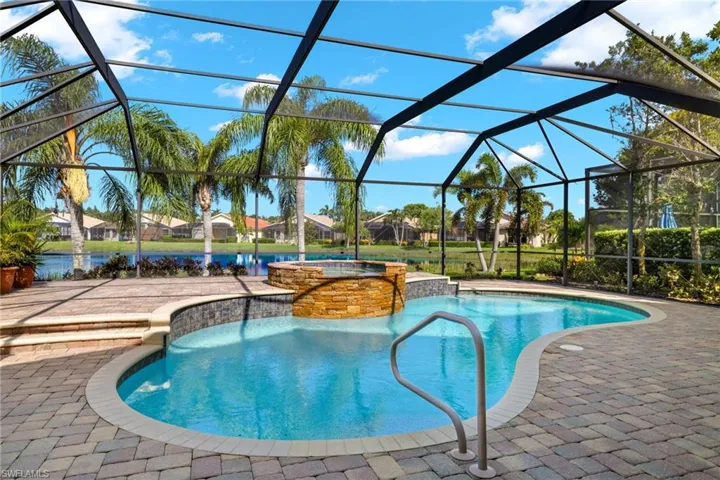 View of swimming pool with an in ground hot tub, a patio, and glass enclosure