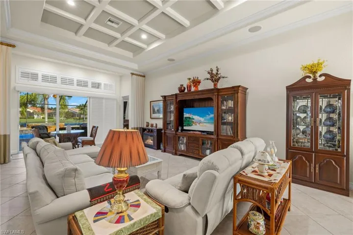 Living room with beam ceiling, light tile patterned flooring, and coffered ceiling