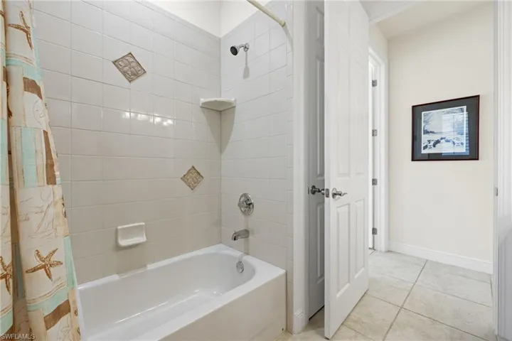 Bathroom with tile patterned flooring and shower / tub combo with curtain