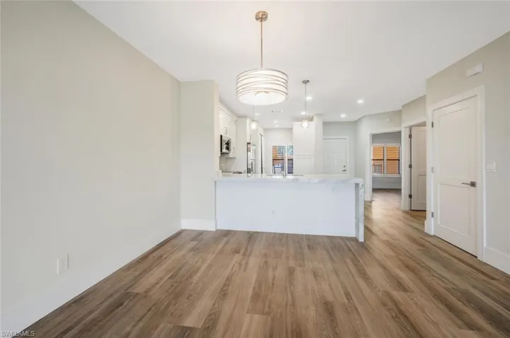 Kitchen featuring white cabinetry, decorative light fixtures, kitchen peninsula, and light hardwood / wood-style floors