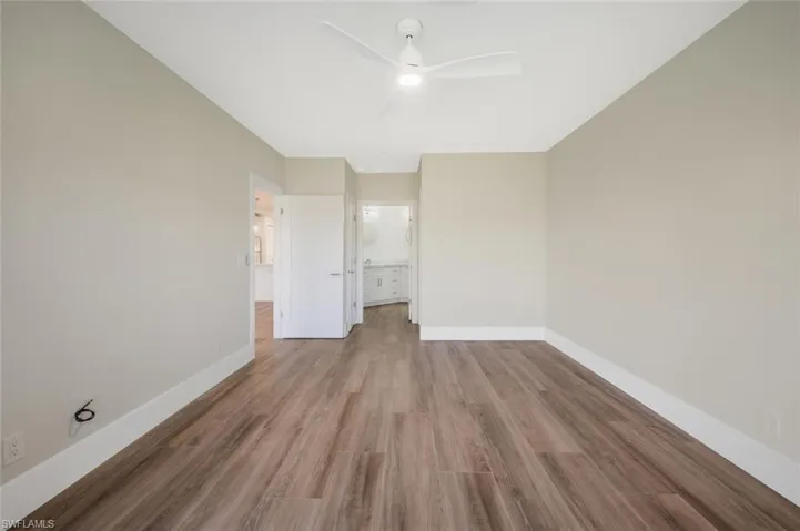 Unfurnished bedroom with ceiling fan, ensuite bath, and light hardwood / wood-style flooring