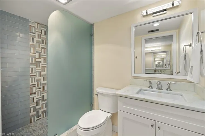 Full bath featuring visible vents, a walk in shower, toilet, and vanity