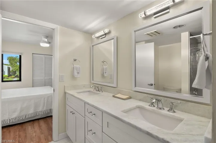 Bathroom with double vanity, wood finished floors, toilet, and a sink