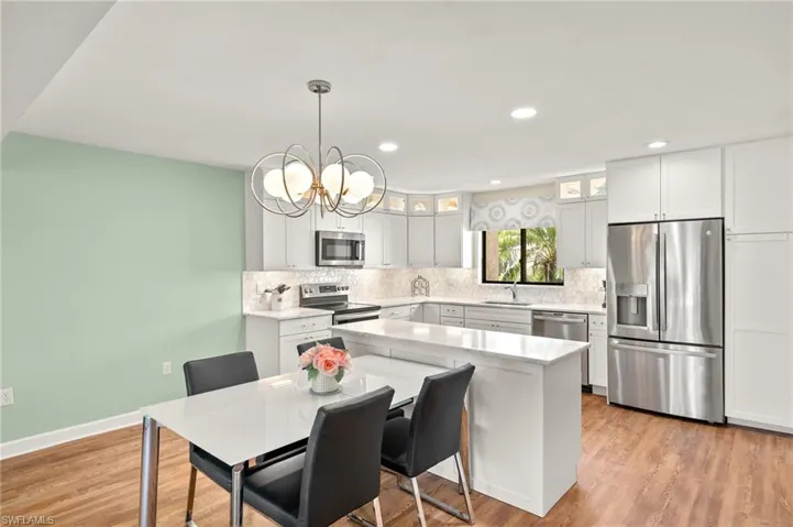 Kitchen featuring light wood-type flooring, backsplash, and appliances with stainless steel finishes