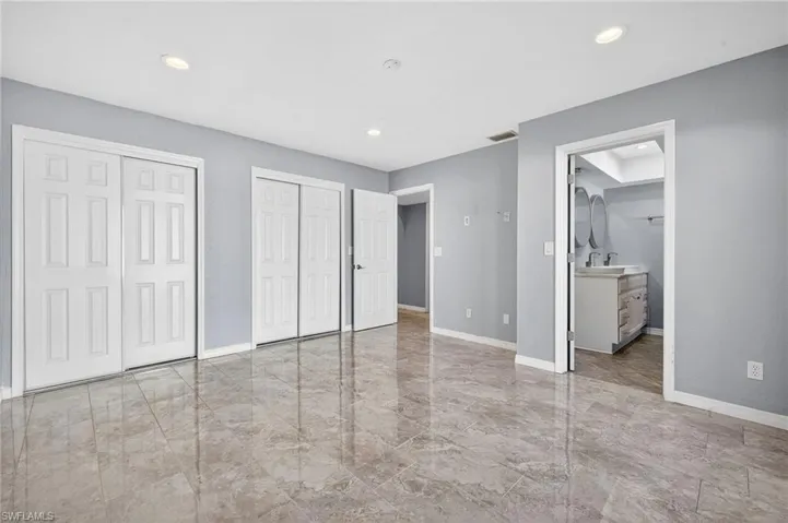 Unfurnished bedroom featuring multiple closets, light marble finish flooring, and recessed lighting