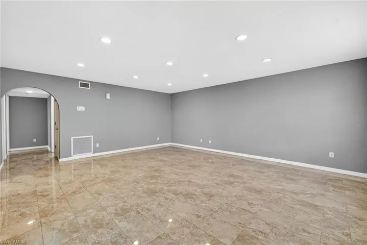 Empty room with recessed lighting and arched walkways
