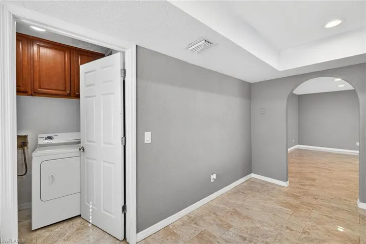 Washroom featuring washer / dryer, arched walkways, recessed lighting, and cabinet space