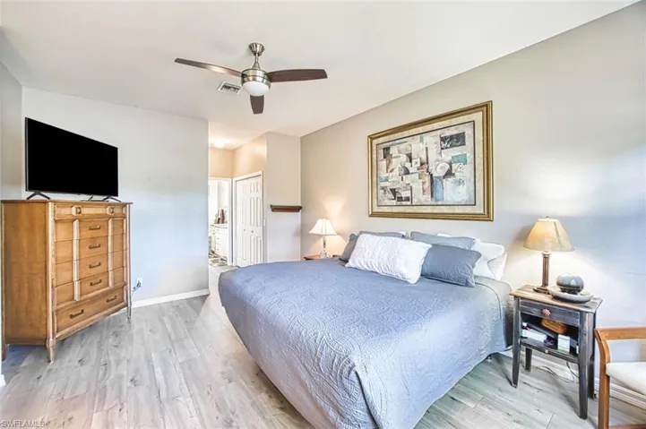 Bedroom featuring light wood-style floors, ceiling fan, a closet, and ensuite bathroom