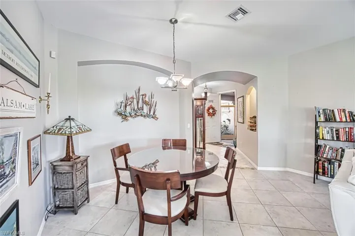 Dining space featuring arched walkways, light tile patterned floors, and a chandelier