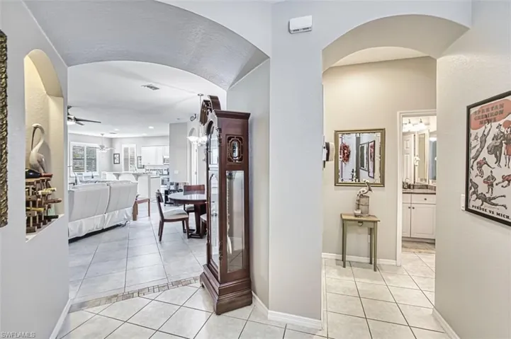 Hall featuring arched walkways and light tile patterned floors