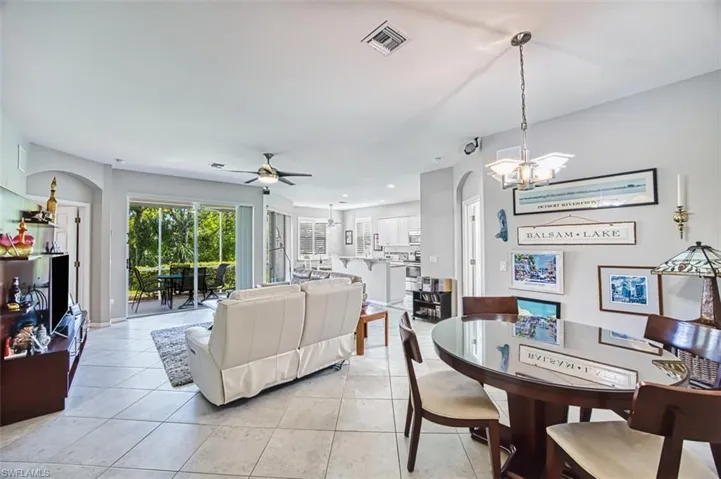 Dining area with arched walkways, light tile patterned flooring, a chandelier, a ceiling fan, and recessed lighting