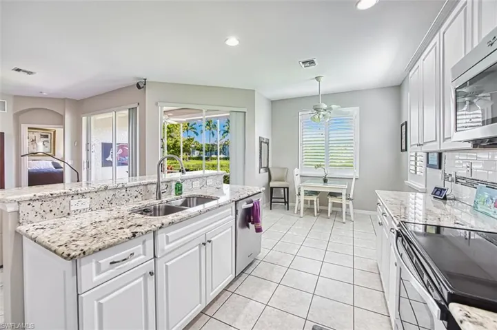 Kitchen featuring white cabinets, appliances with stainless steel finishes, light stone counters, recessed lighting, and light tile patterned floors