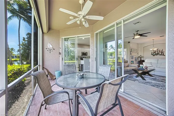Sunroom with ceiling fan, a chandelier, a water view, outdoor dining area, and a patio