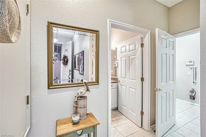 Hallway featuring a textured wall and light tile patterned floors