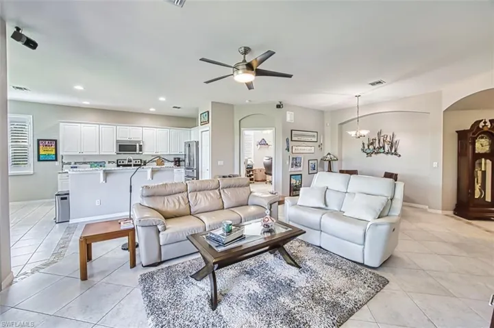Living room with light tile patterned flooring, arched walkways, a chandelier, ceiling fan, and recessed lighting