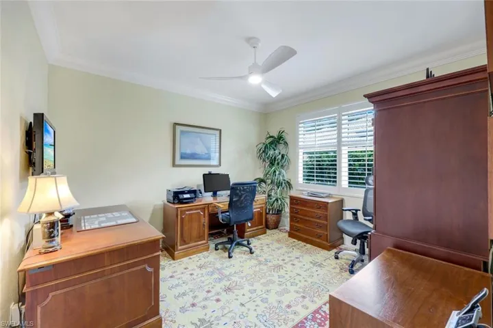 Bedroom with plantation shutters and large closet, currently set up as office