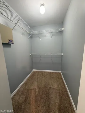 Walk in closet featuring dark colored carpet