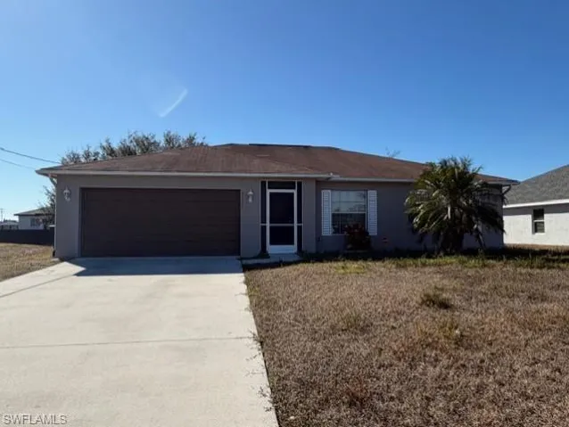 Ranch-style home with concrete driveway, stucco siding, a garage, and a front yard