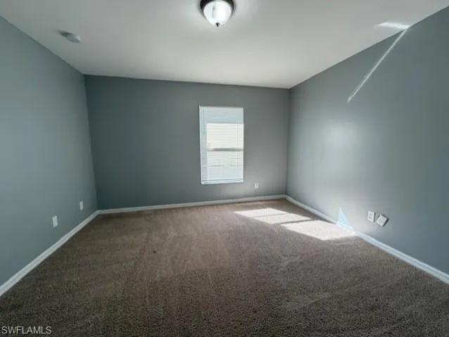 Carpeted empty room featuring baseboards