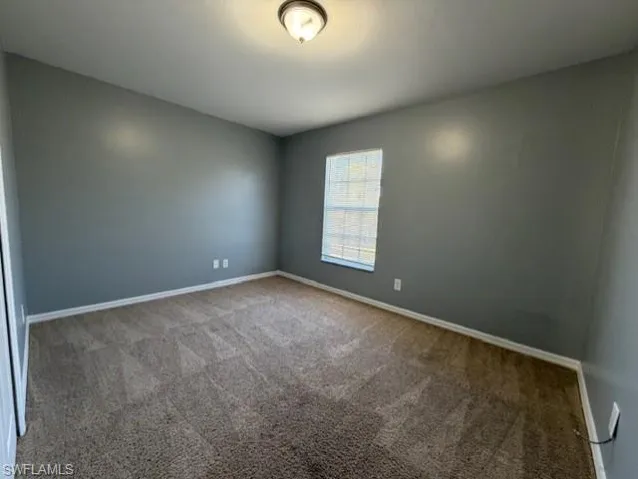 Carpeted spare room featuring baseboards