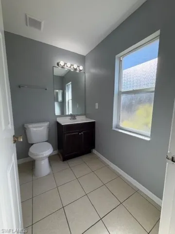 Bathroom featuring vanity, light tile patterned flooring, and vaulted ceiling