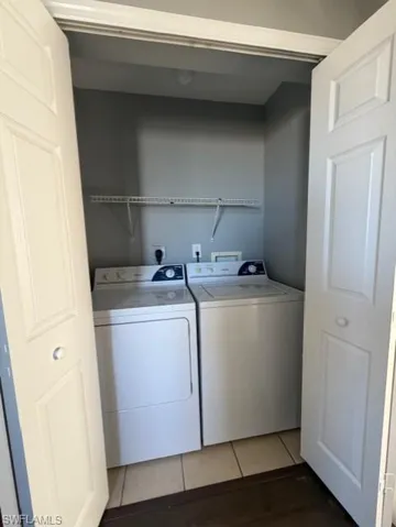 Laundry area featuring light tile patterned floors and washing machine and clothes dryer
