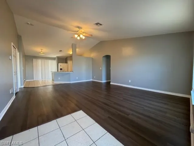 Unfurnished living room with arched walkways, light wood-type flooring, and a ceiling fan