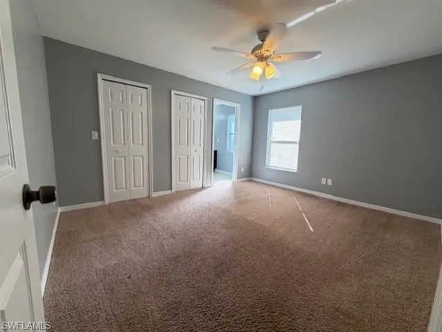 Unfurnished bedroom featuring carpet, two closets, a ceiling fan, and connected bathroom