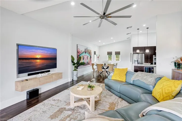 Living area featuring wood finished floors, recessed lighting, a ceiling fan, high vaulted ceiling, and beverage cooler