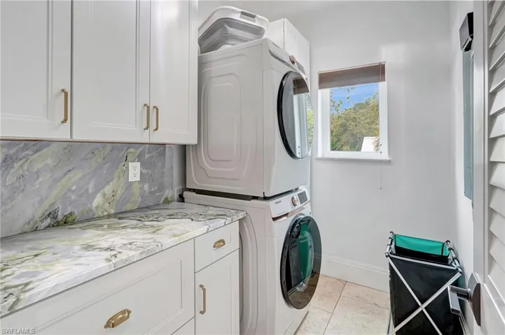 Laundry room featuring cabinet space, stacked washer / dryer, and light tile patterned flooring